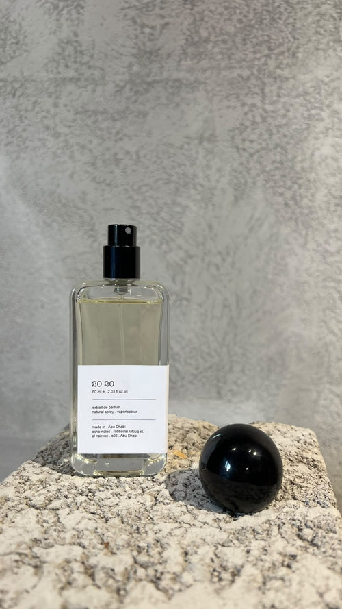 Echo Notes 2020 perfume bottle surrounded by fresh blood oranges, dewy violet leaves, jasmine sambac, and lotus blossoms.