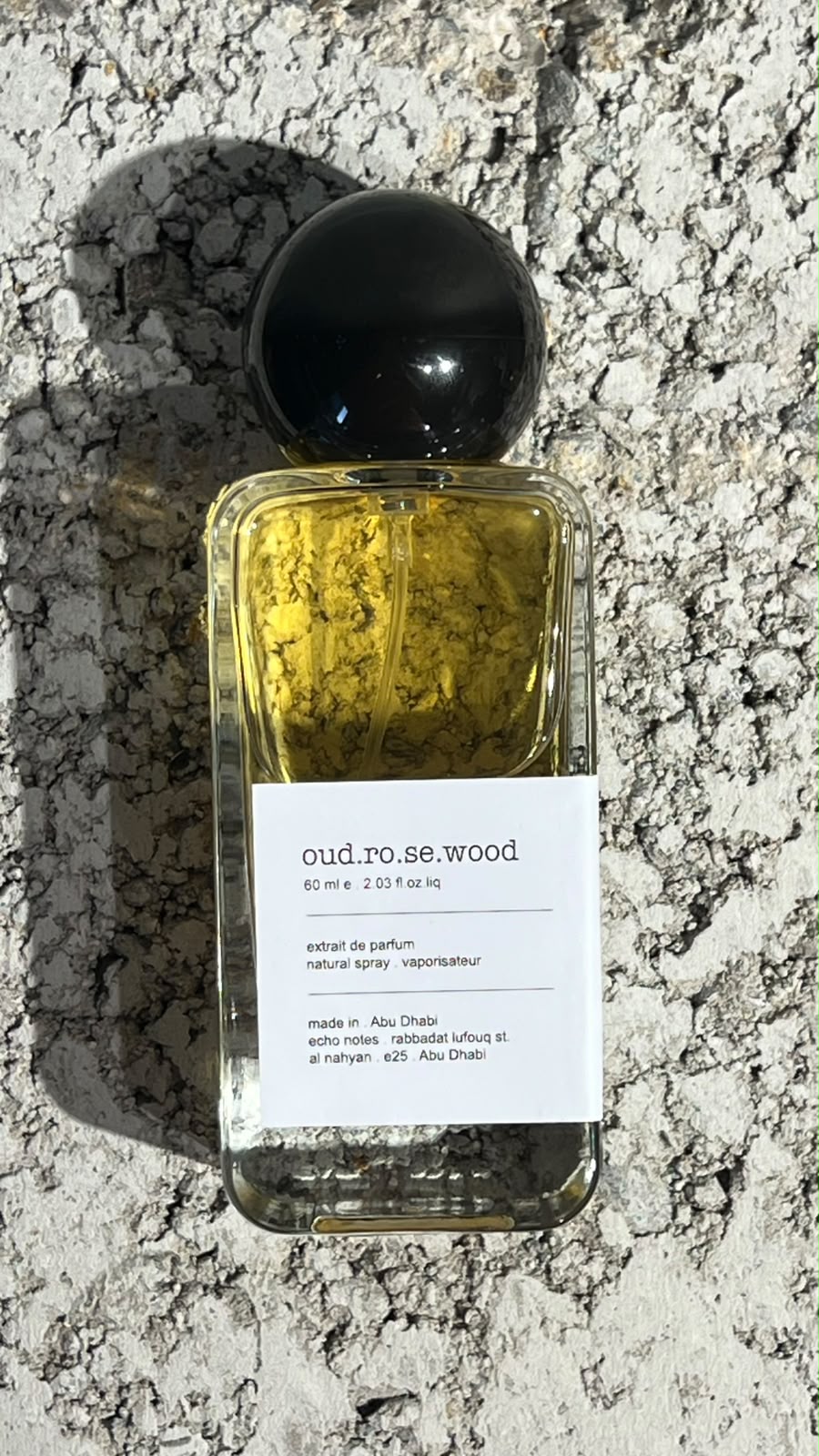 Echo Notes Oud Rosewood perfume bottle surrounded by fresh raspberries, sweet quince, dark oud, and rich rosewood.