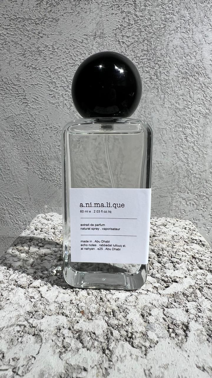 Echo Notes Animalique perfume bottle surrounded by bergamot, lemon slices, delicate violet blooms, soft suede, and tobacco leaves.