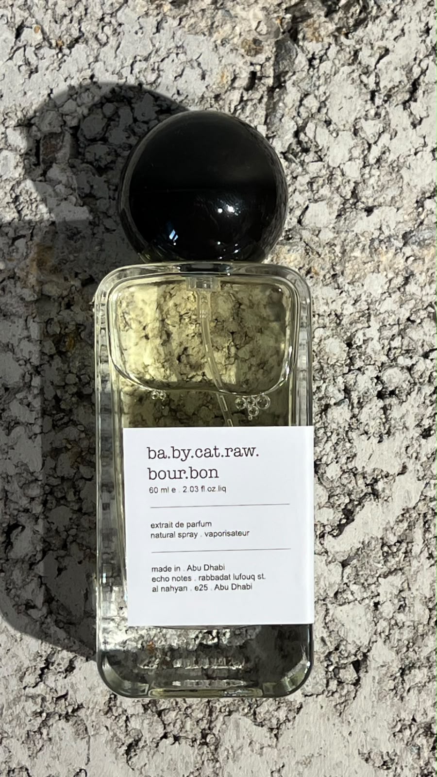 Echo Notes Babycat Raw Bourbon perfume bottle surrounded by black and pink peppercorns, saffron threads, and vanilla pods.