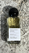 Echo Notes Black Incense Malaki perfume bottle surrounded by a piece of leather, rising incense smoke, oud chips, and olibanum resin.