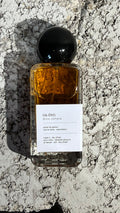 Echo Notes Caden perfume bottle surrounded by saffron threads, cardamom pods, amber liquor, soft suede, and coffee beans.