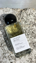 Echo Notes Comme des Garcons 2 perfume bottle surrounded by fresh tea leaves, dark calligraphy ink, spices, and incense resins.