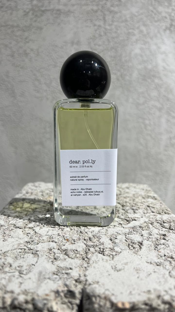 Echo Notes Dear Polly perfume bottle surrounded by fresh bergamot, red apple slices, dark black tea leaves, and black amber.