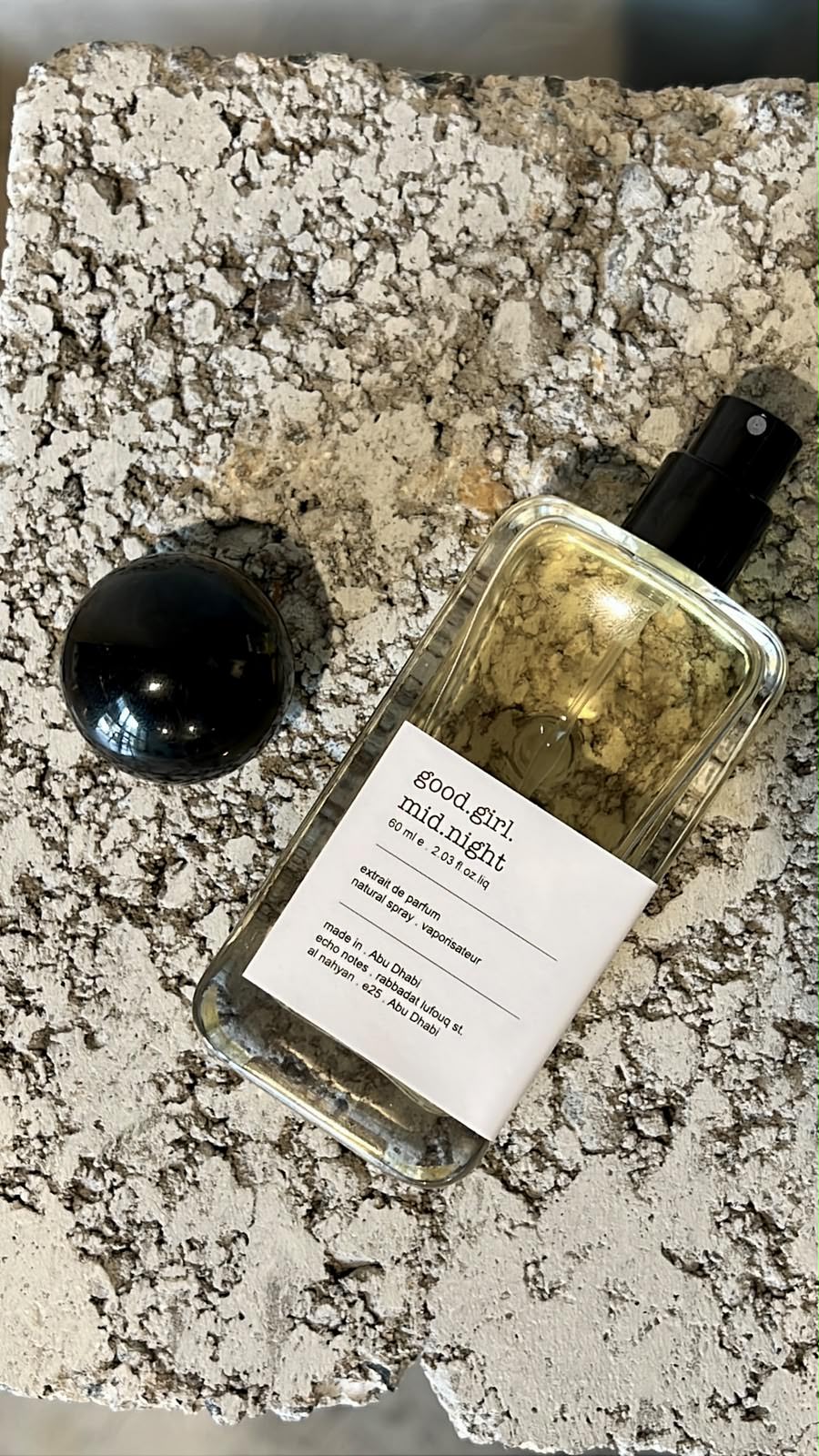 Echo Notes Good Girl Midnight perfume bottle surrounded by sweet almond, white tuberose petals, and vanilla beans.