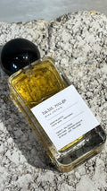 Echo Notes Habit Rouge perfume bottle surrounded by vanilla pods, amber rum, dried patchouli leaves, and fresh bergamot.