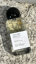 Echo Notes Moonlight Patchouli perfume bottle surrounded by deep patchouli leaves, dark cacao, and supple suede leather.