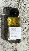 Echo Notes Mystery Tobacco perfume bottle surrounded by golden osmanthus blossoms, cured tobacco leaves, and tonka beans.