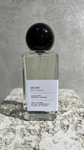 Echo Notes Sellier perfume bottle surrounded by black tea leaves, soft cashmeran fabric, dark leather, birch, and oakmoss.