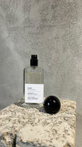Echo Notes Tygar perfume bottle surrounded by fresh grapefruit halves, sliced ginger root, and crystalline ambroxan.