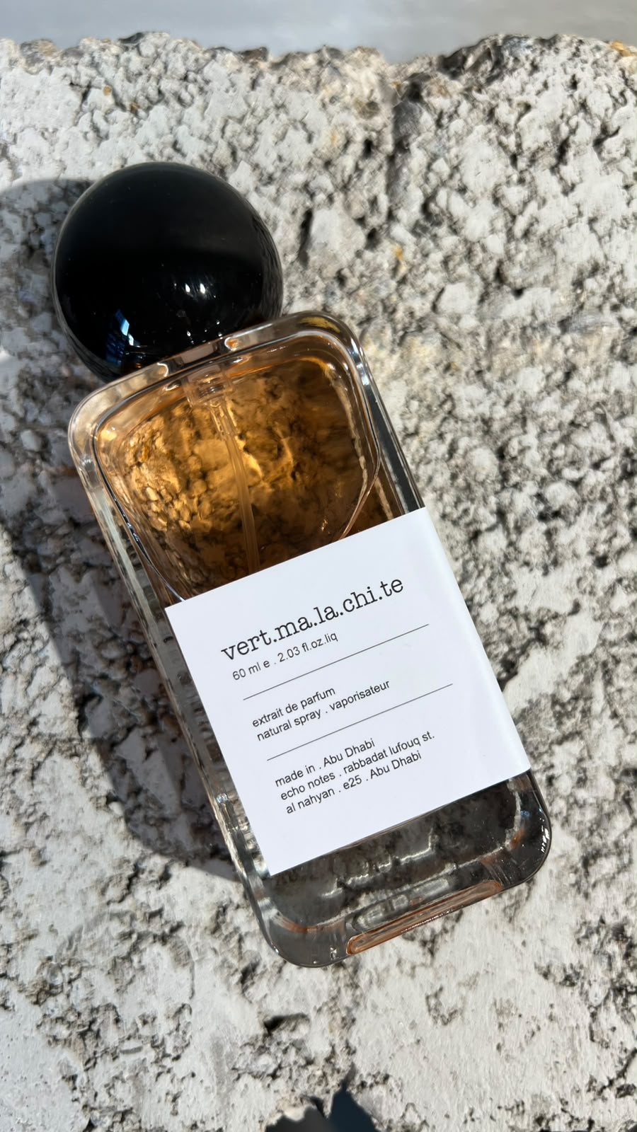 Echo Notes Armani Prive Vert Malachite perfume bottle surrounded by bitter orange leaves, jasmine sambac flowers, and vanilla pods.